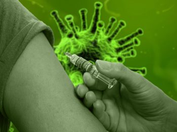 Impfung Spritze am Oberarm, im HIntergrund ein Covid19 Virus